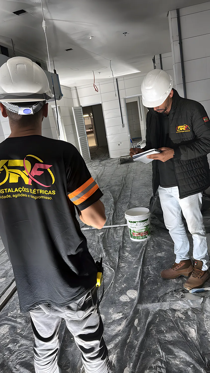 Dois profissionais da RF, com o uniforme da empresa, conferem o projeto dentro da obra