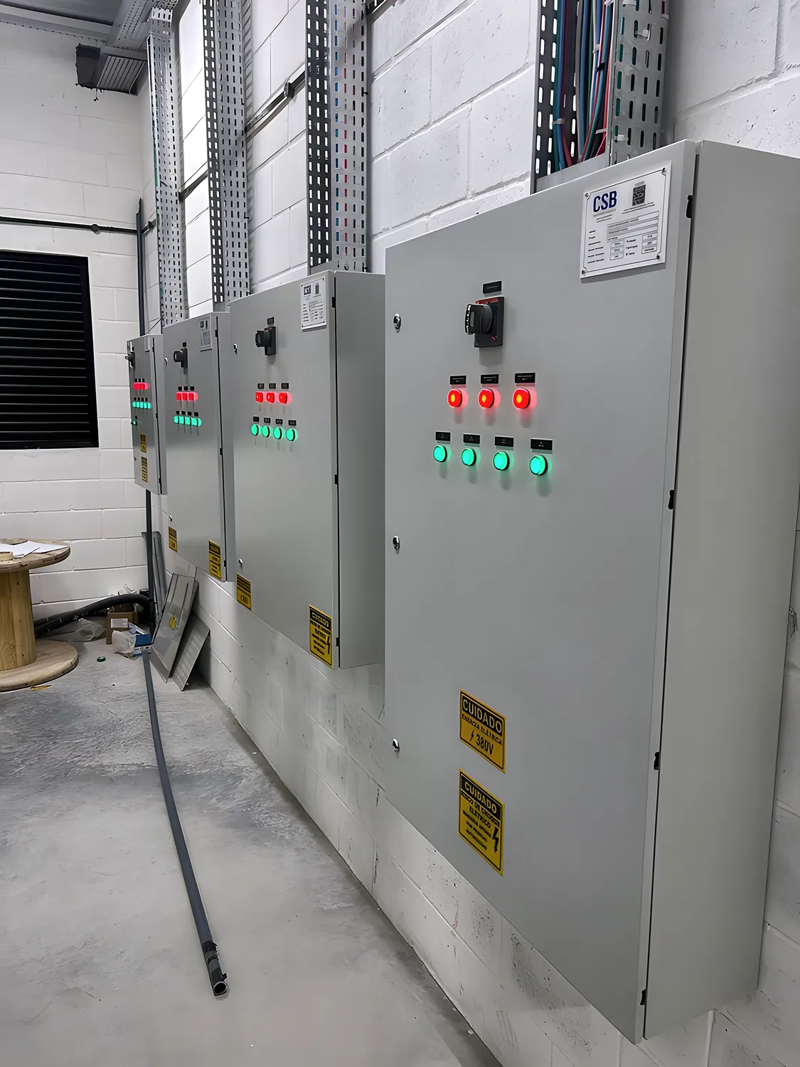 Linha de painéis elétricos montados na Olsen, com sinaleiras vermelhas e verdes e placas de advertência